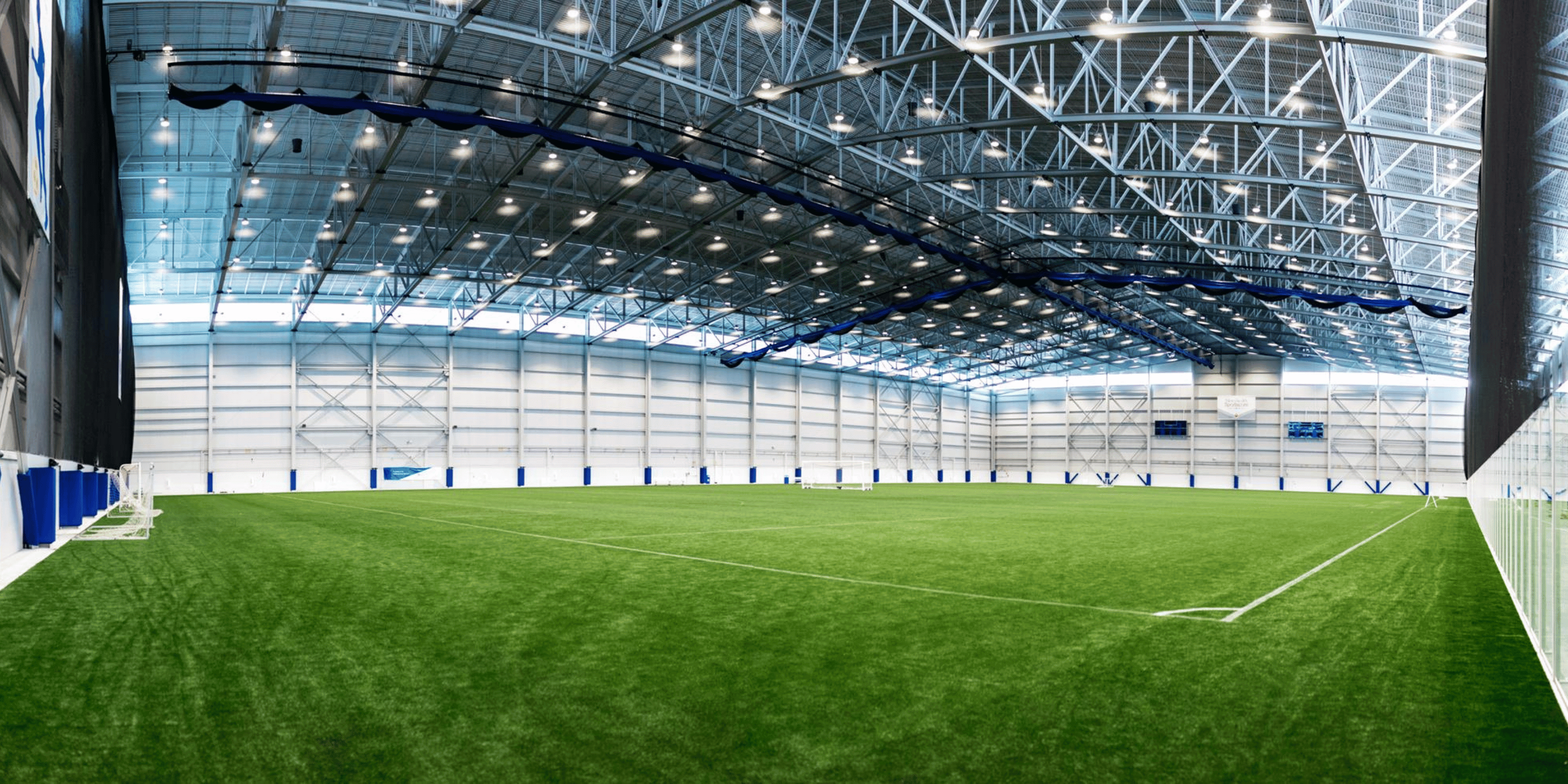 Indoor baseball sports complex with green turf field and divider curtain netting