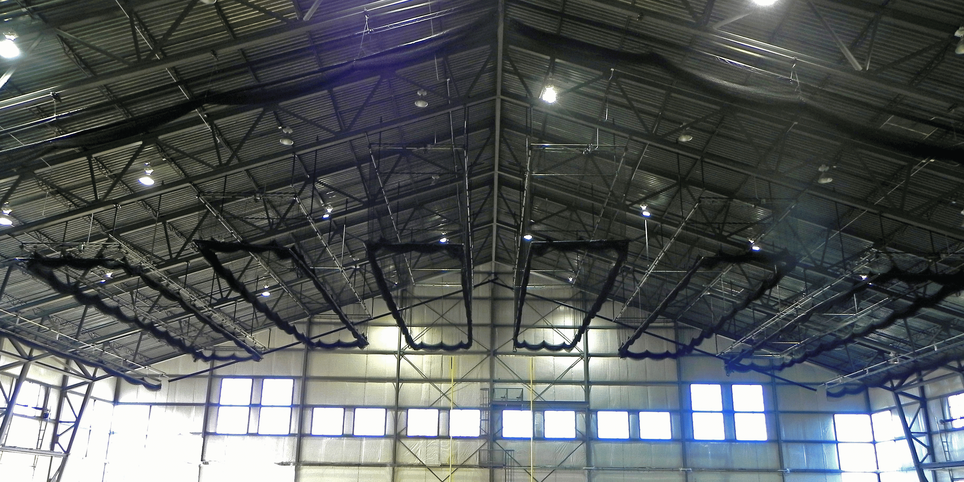 Indoor batting cage nets lifted up to the ceiling in sport complex facility.